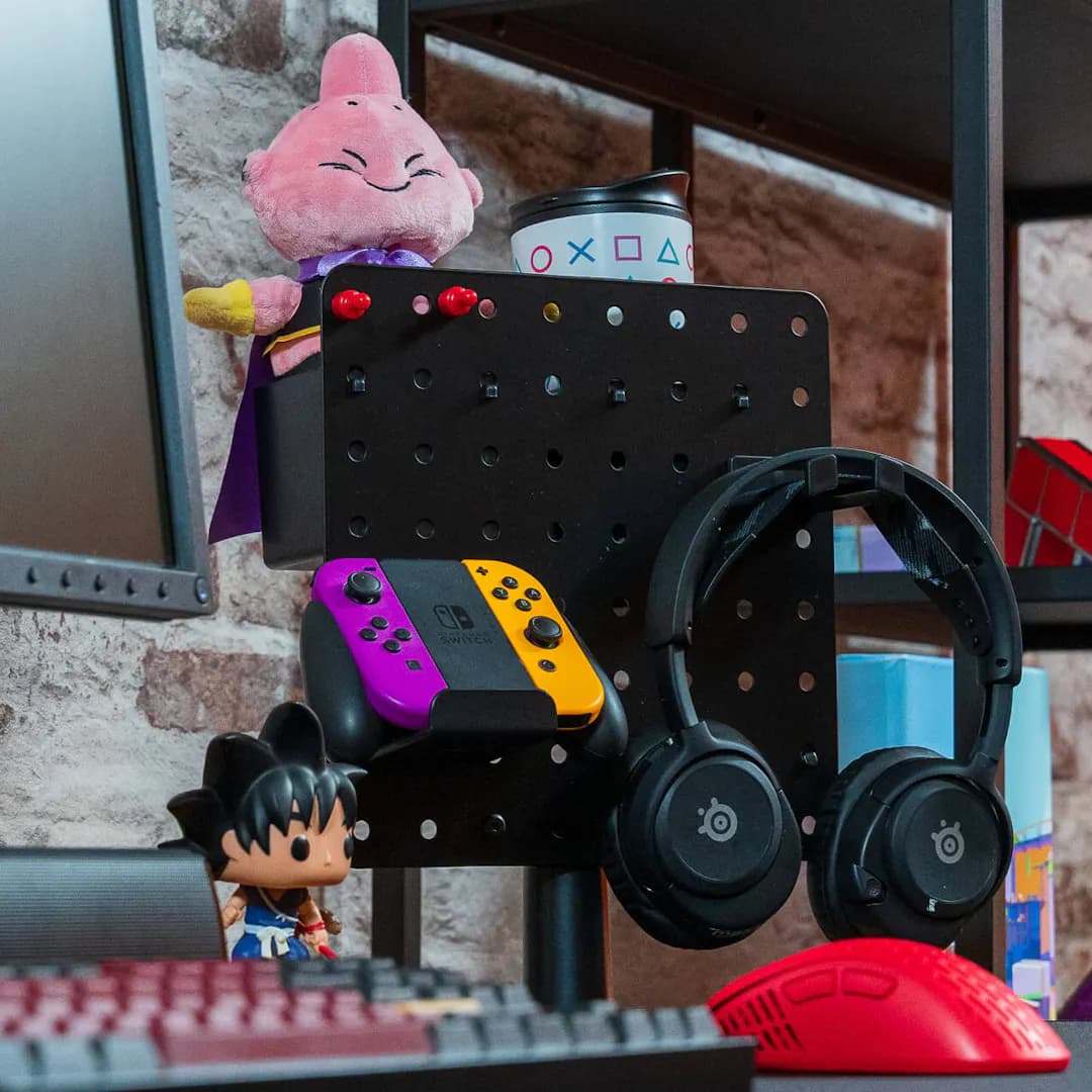Pegboard in gaming setup with headphones, Nintendo Switch Joy-Cons, Funko Pop figures and a cup holder for organised and space-saving storage of gaming accessories.