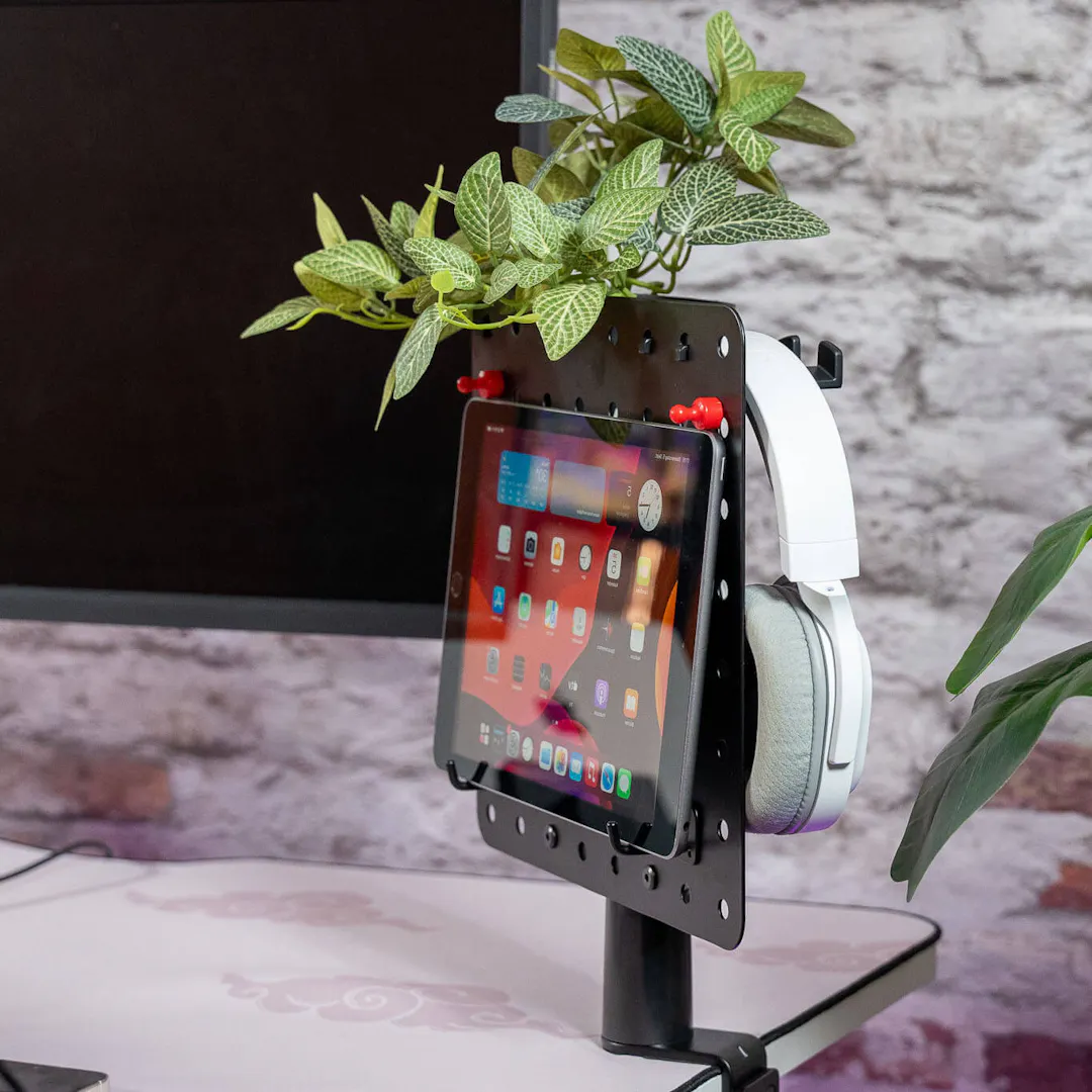 Pegboard as a desk organiser with tablet holder, headphones and decorative plant for a tidy and stylish working environment.