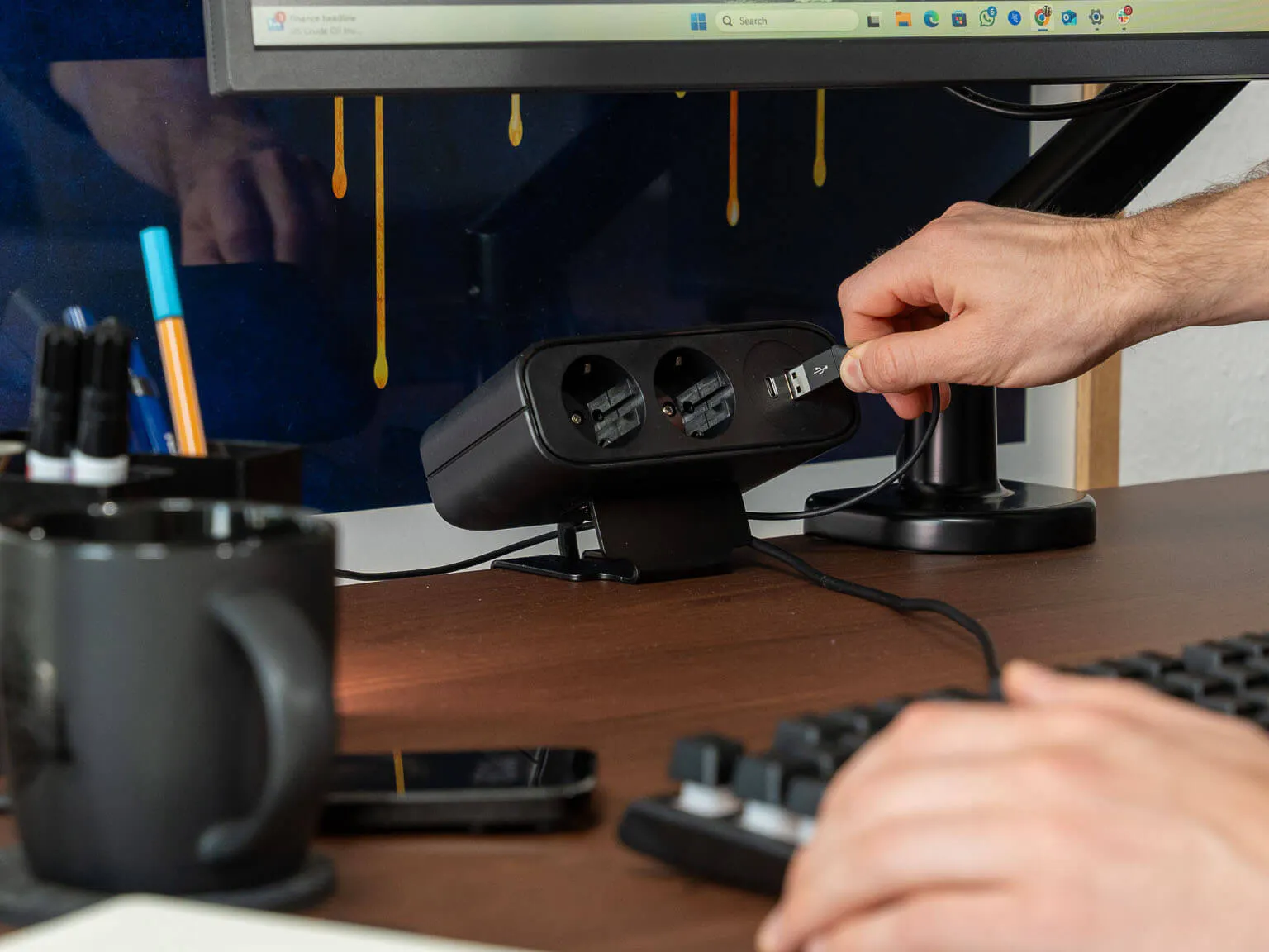 LeetDesk PowerFlak clamp-on socket on a wooden desk, charging devices via USB port.