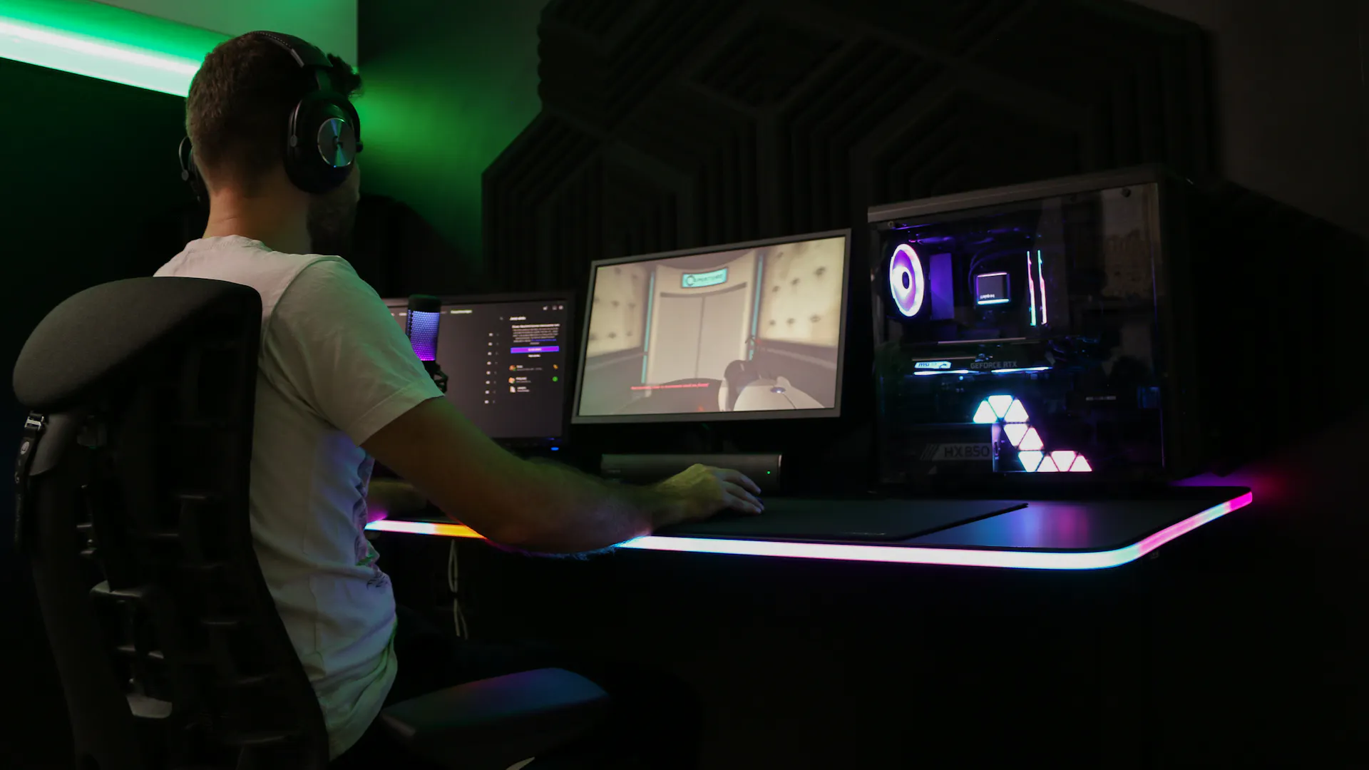 Jemand sitzt am RGB beleuchteten LeetDesk AURA und streamt.